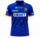 Barbados Tridents CPL royal blue cricket jersey front view with trident watermark graphics and yellow collar trim